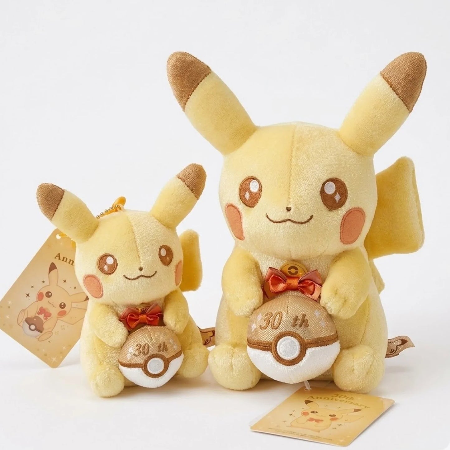 Two Pikachu plush toys with '30th' on their bellies on a white background